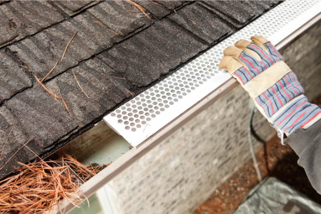 Gutter guard installation by a worker with gloves on